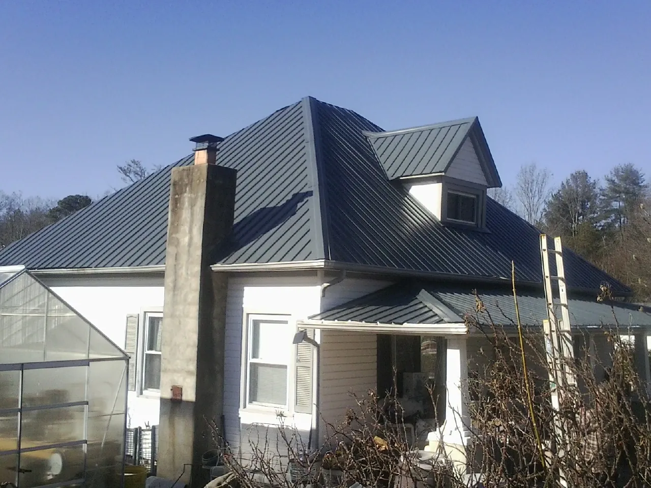 Dark blue standing seam metal roof on a white farmhouse with dormer — Slate & Tile Roof Repair by Roofing Brothers in Westfir
