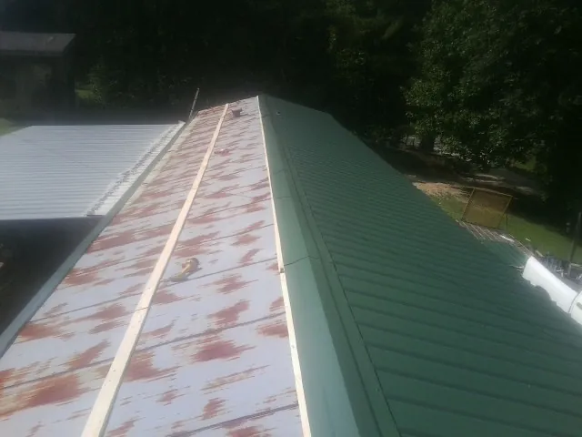 Old rusted panels beside newly installed green metal roofing — Wind Damage Roof Repair by Roofing Brothers in Westfir