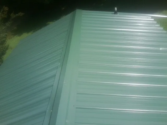 New green metal panels meeting at the ridge of a roof — Flat Roof Repair work by our crew in Westfir