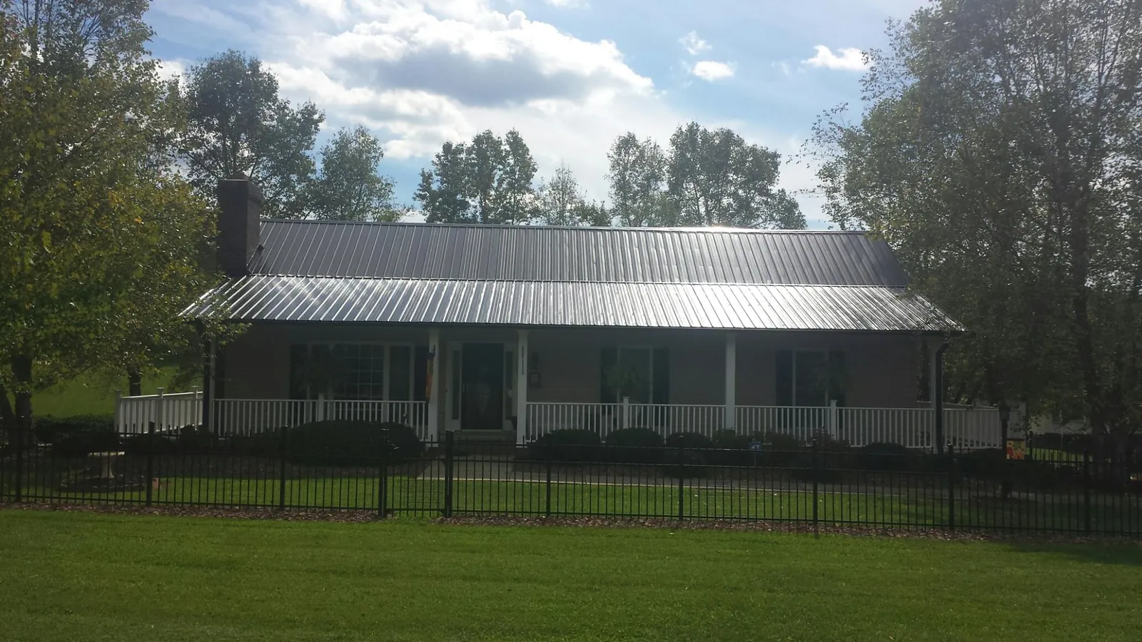 Gray metal roof on a brick ranch with a full width front porch — Gutter Guard Installation work by our crew in Westfir