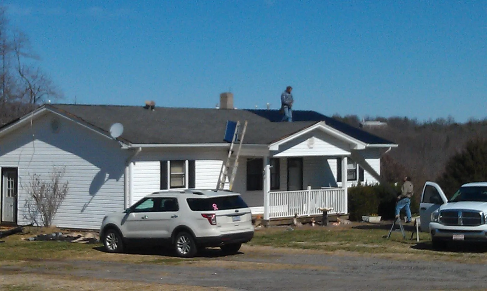 Roofers stripping shingles from a white ranch house roof in Westfir
