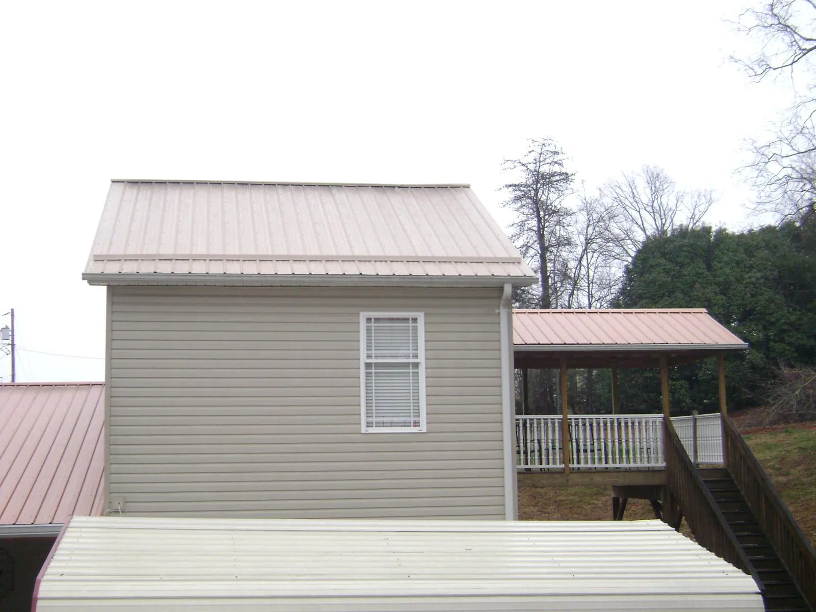 Tan metal roofs on a two story addition and attached porch, from a Roof Replacement job in Westfir