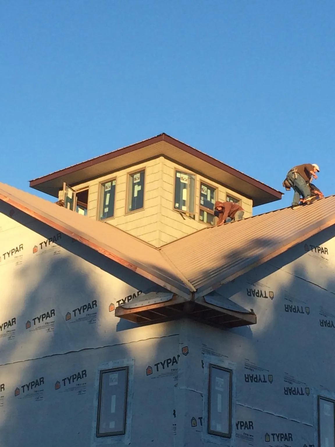 Roofers working around a rooftop cupola on a new metal roof at sunset — Roof Waterproofing in Westfir by Roofing Brothers